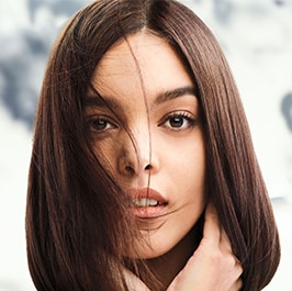woman with brown straight har with foliage in the background