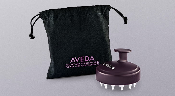 invati scalp brush and black drawstring bag on purple-grey background
